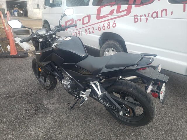 Rear three-quarter view of the CB300F with the shop bay open behind