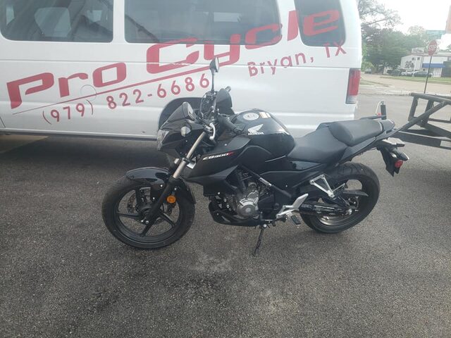 Left side profile of a black Honda CB300F outside the shop