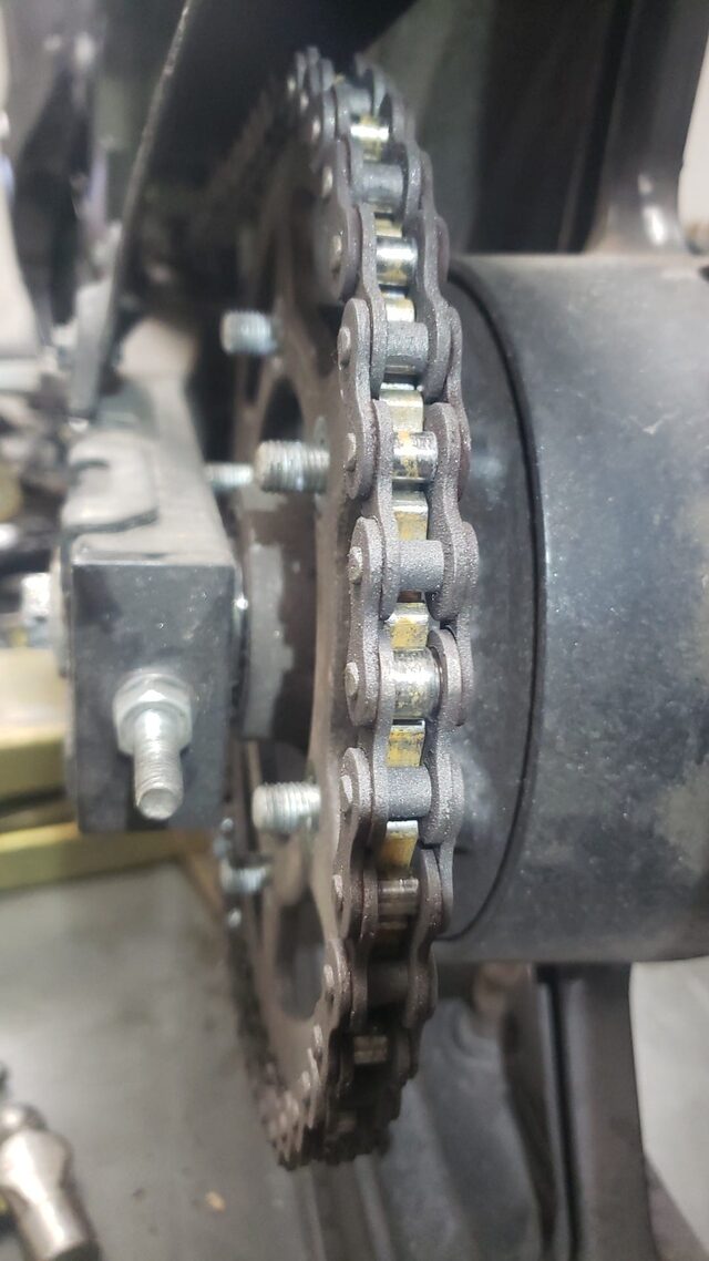 A worn chain and rear sprocket on a bike up on the lift
