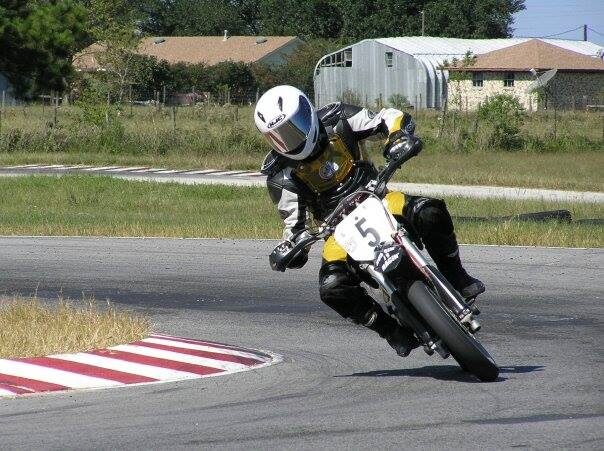 A supermoto racer knee-down through a corner at a track day
